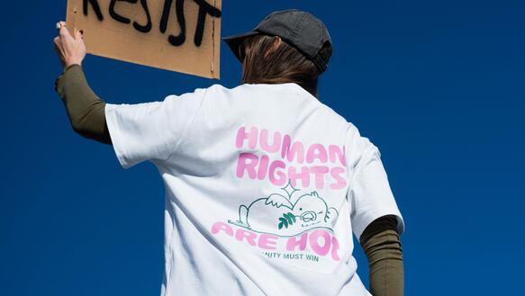 Human Rights are hot junge Frau im Amnesty T-Shirt "Human Rights are hot" und einem Resist Protest Plakat